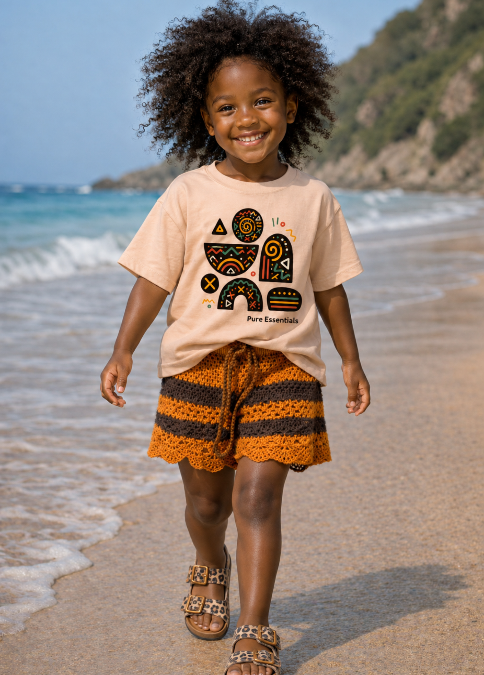 Child walking on a beach wearing a beige t-shirt with a graphic design and striped shorts.