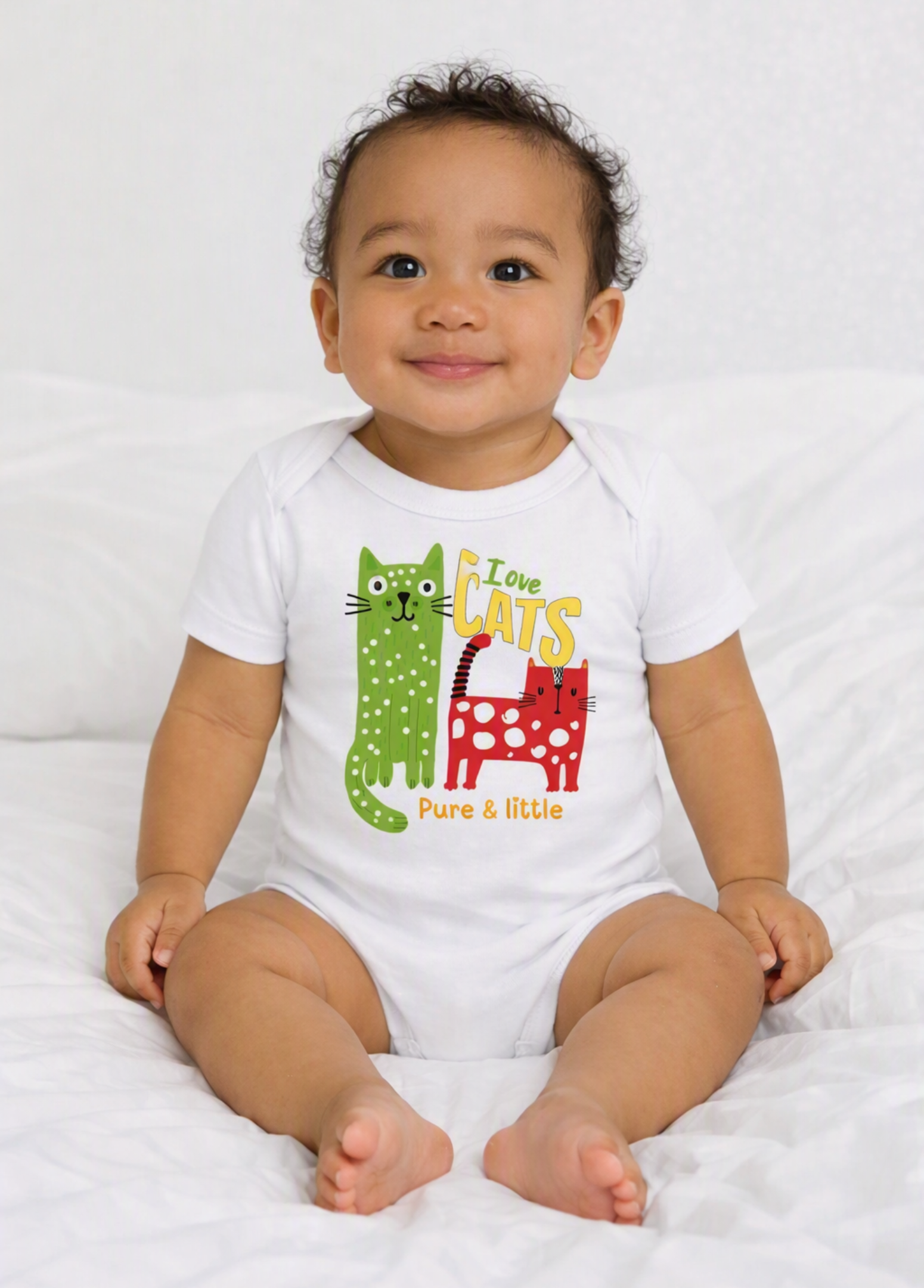 A baby sitting on a white bed wearing a white short-sleeve bodysuit with a colorful graphic of two cartoon cats and the text 'Love CATS Pure & little'. A 'Made with AI' watermark is visible in the top right corner.