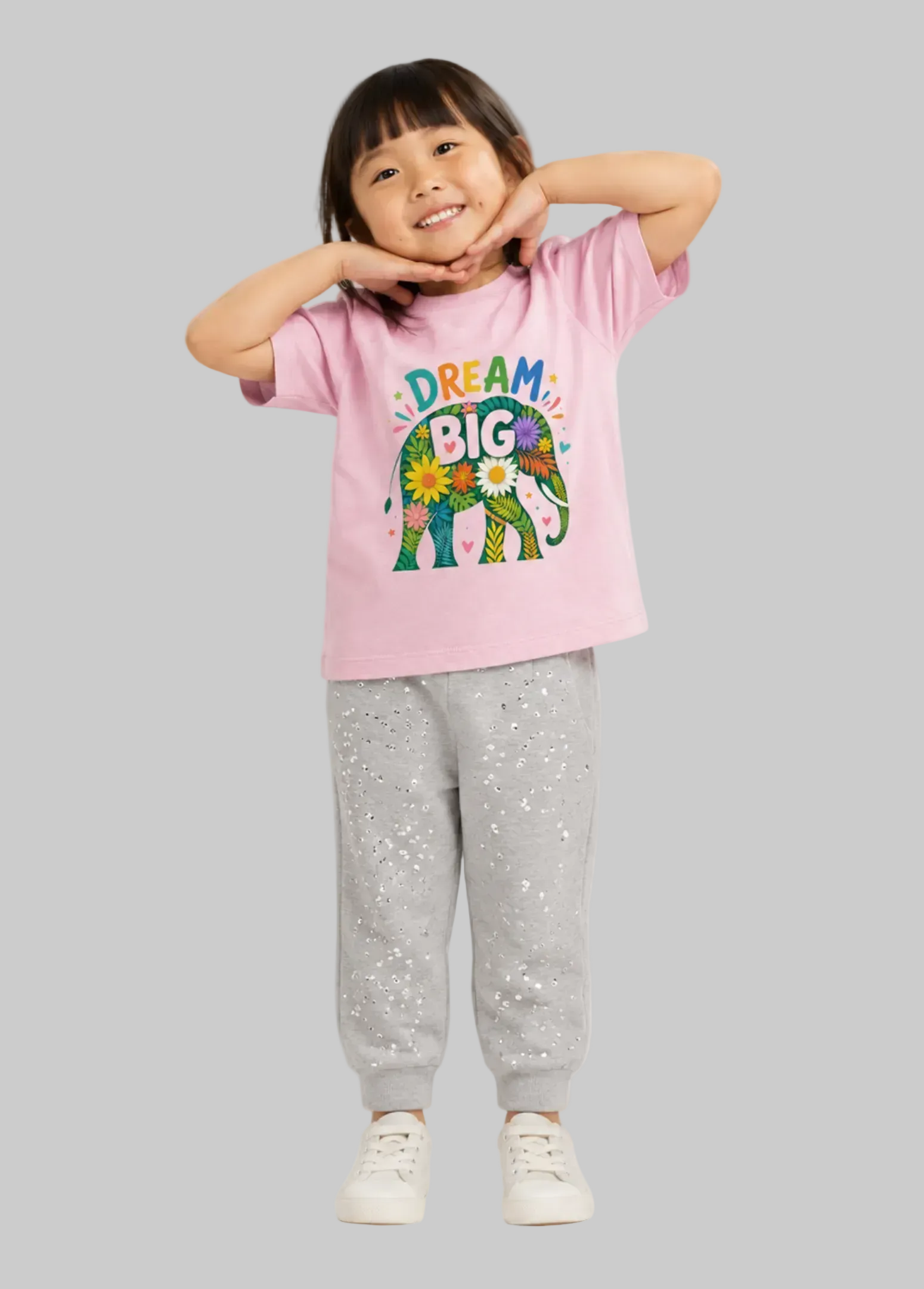 Child wearing a pink 'Dream Big' t-shirt and gray pants on a light gray background